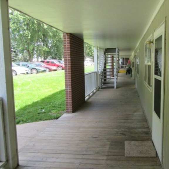 a long porch outside of a house with wood floors