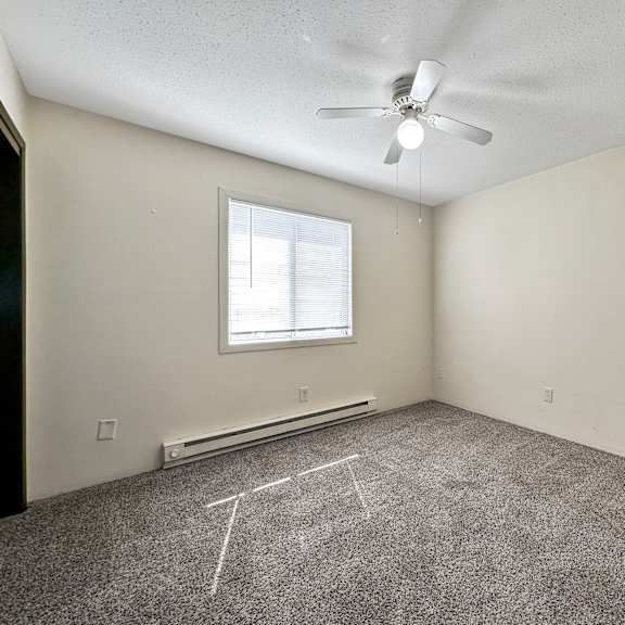 a room with a ceiling fan and a window.