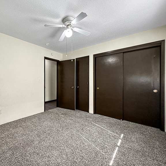 a room with a ceiling fan and carpeted floor.