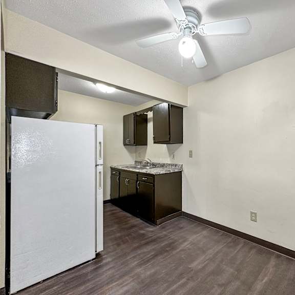 a kitchen area with a white refrigerator and a ceiling fan.