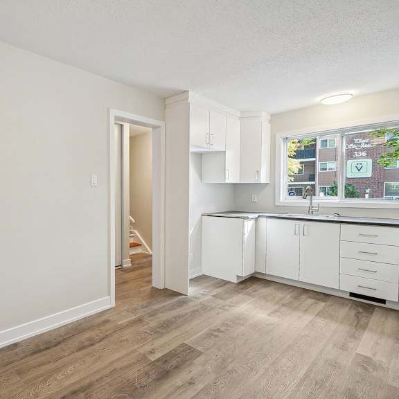 a room with a doorway leading to a kitchen area.