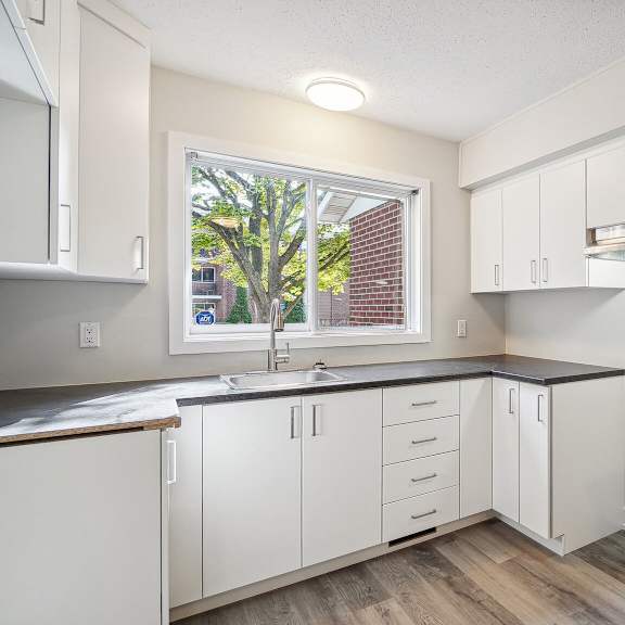 a kitchen with white cabinets and a window.