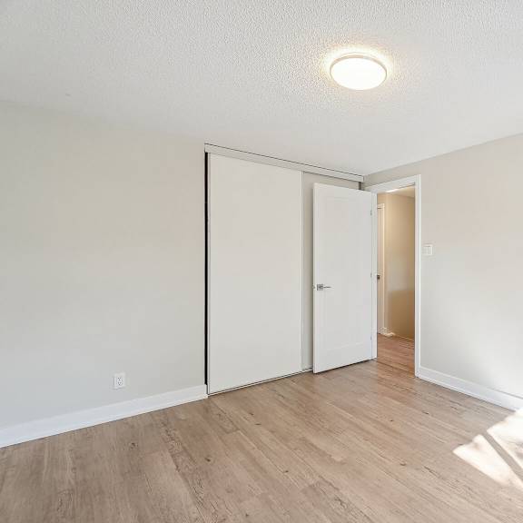 a room with a white ceiling and a wooden floor with a door on the right.