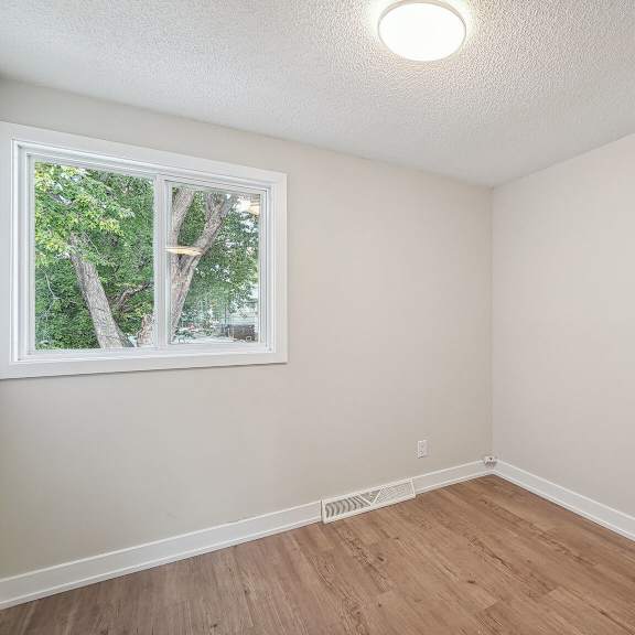 a room with a window and wooden flooring.