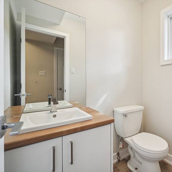 a white toilet sits in a bathroom with a wooden counter and a mirror.
