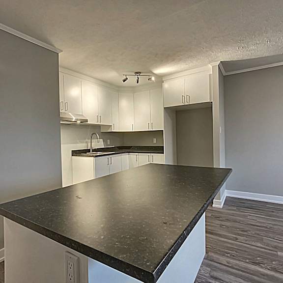 a kitchen with a black countertop and white cabinets.
