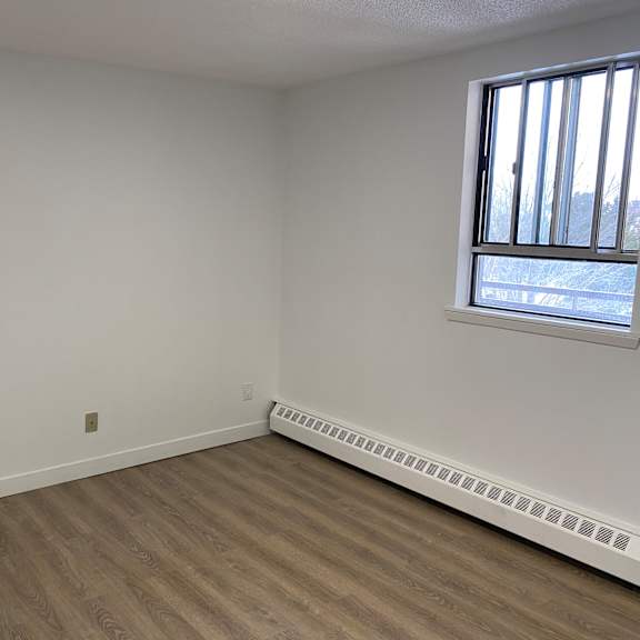 empty room with a window and a radiator on the wall.
