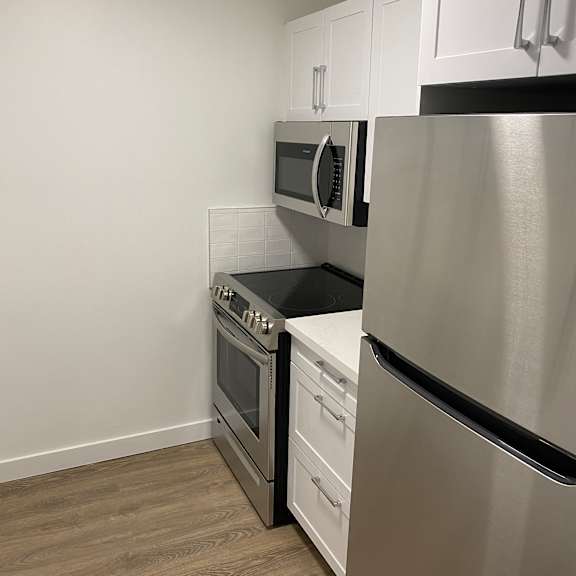 a kitchen with a stainless steel range hood and a white wall.