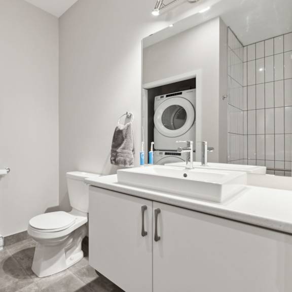 a white bathroom with a toilet, sink, and cabinet.