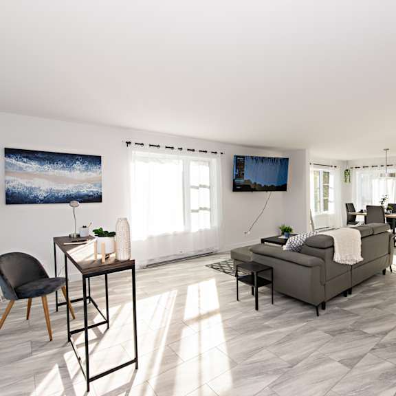 a living room with a grey sofa, a black chair, a wooden table, and a painting on the wall.