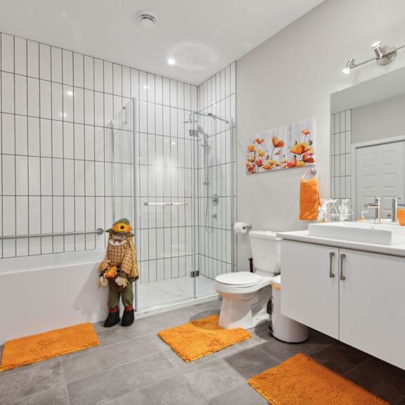 a bathroom with a white tile shower and a white toilet.