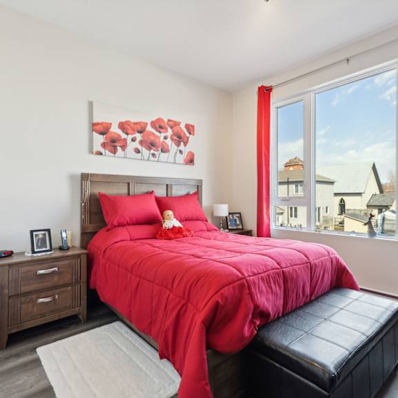 a bedroom with a red bedspread and a red curtain.