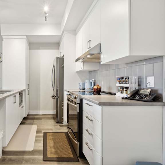 a kitchen with white cabinets and a brown rug on the floor.