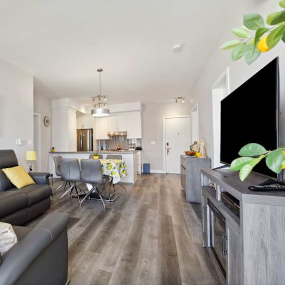 a living room with a grey couch and a painting of a tree on the wall.