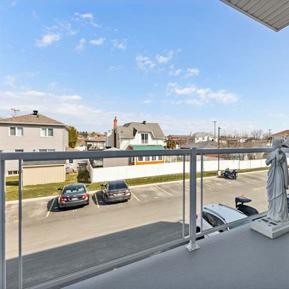 a balcony with a chair and a statue overlooking a parking lot.