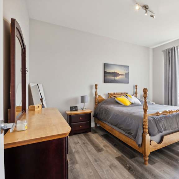 a bedroom with a four poster bed and a wooden dresser.