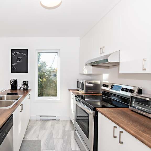 a kitchen with a clock on the wall and a window with a view of trees.