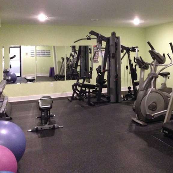 a gym with a variety of equipment including treadmills, weights, and exercise balls.