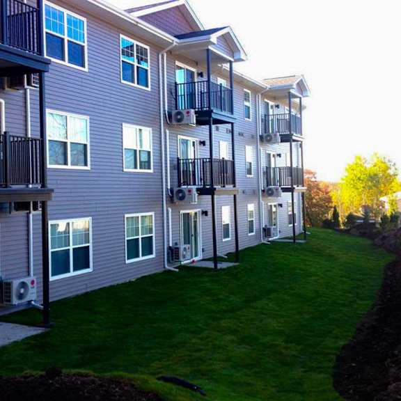 apartment building with balconies and green lawns.