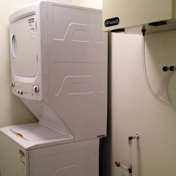 a pair of white front loading washing machines in a laundry room.