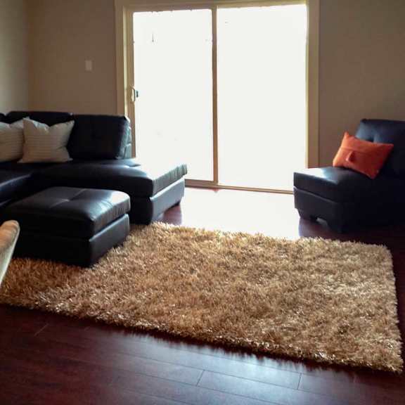 a living room with a black couch and a brown rug.