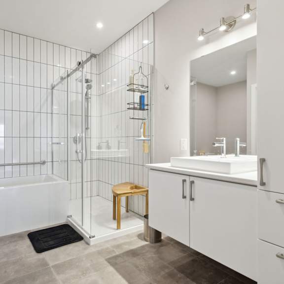 a white bathroom with a glass shower enclosure and a white bathtub.