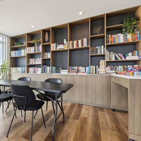 a room with a table, chairs and a bookshelf.