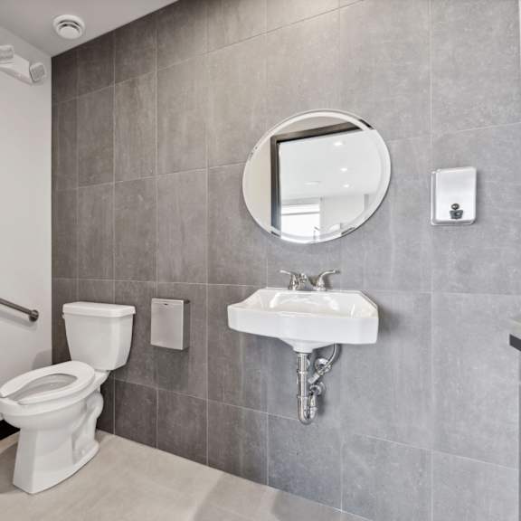 a bathroom with a toilet, sink, and mirror.