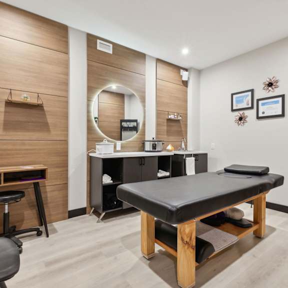 a room with a massage table and a mirror on the wall.