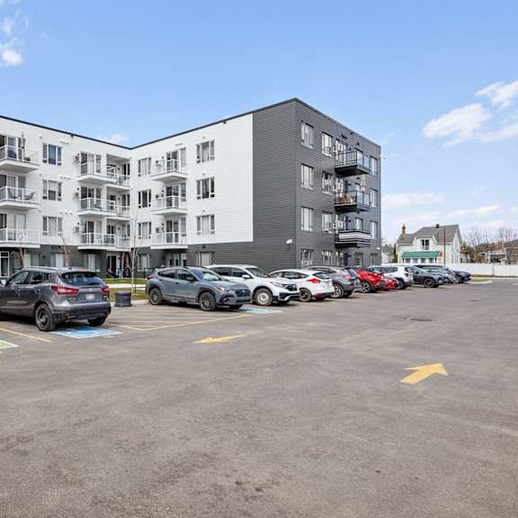 a parking lot with cars and apartment buildings in the background.