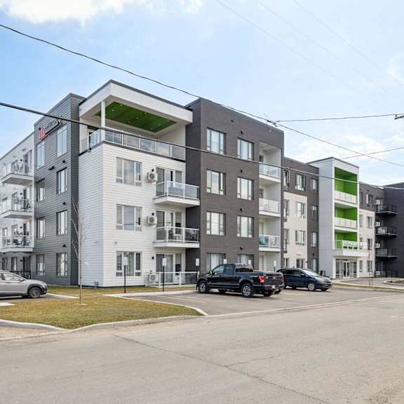 a modern apartment complex with cars parked in front.