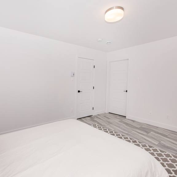 a bedroom with a bed, pillows, and a grey and white floor.