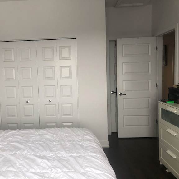 a white bed with a white comforter and pillow in a white room.
