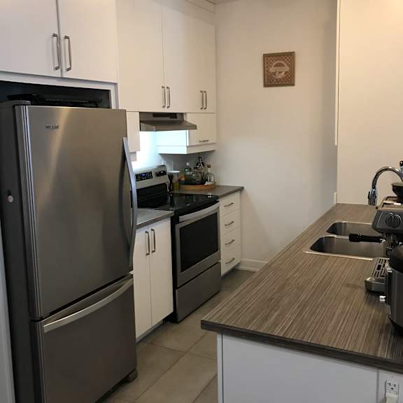 a modern kitchen with a stainless steel refrigerator and white cabinets.