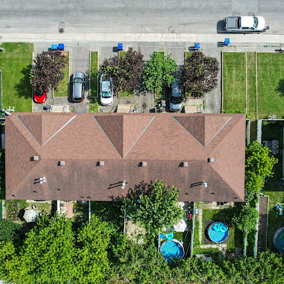 a bird's eye view of a residential area with houses, cars, and a pool.