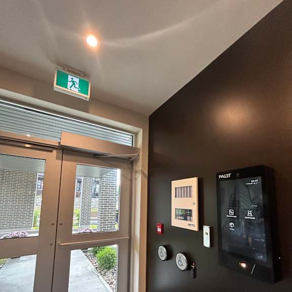 a black wall with a green exit sign above it.