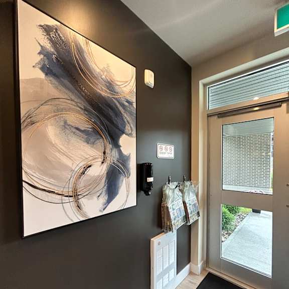 a hallway with a large painting on the wall and a door with a window.