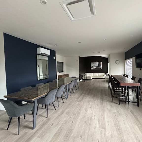 a long dining table with chairs is in a room with a wooden floor.