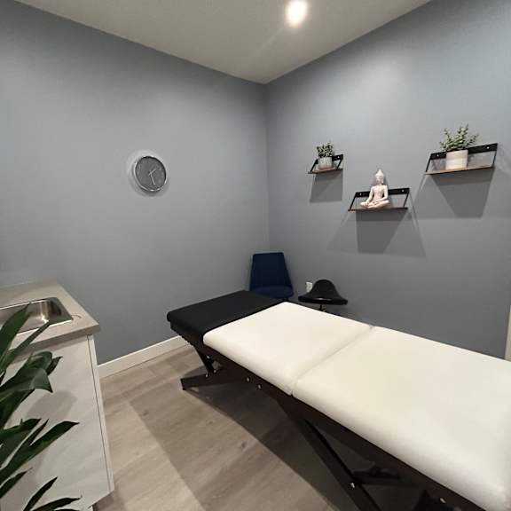a room with a massage table and a sink.