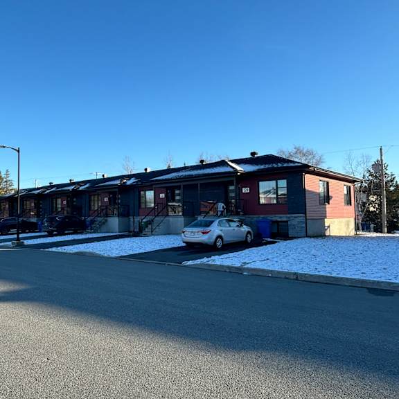 a building with a red and blue exterior is surrounded by a parking lot with a car parked in front.