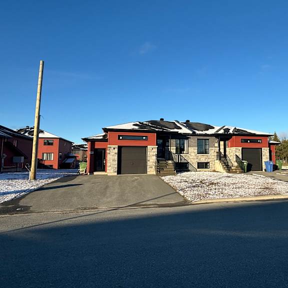 a house with a red and brown exterior is surrounded by snow.