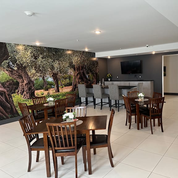 a modern dining room with a large mural of an olive grove on the wall.