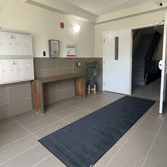 a hallway with a bench, a door, and a wall-mounted phone.