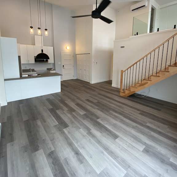 a modern kitchen with a staircase and a ceiling fan.