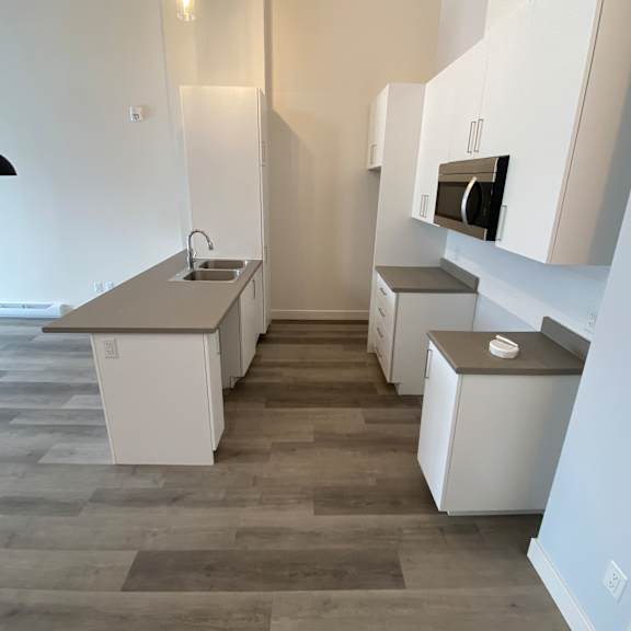 a kitchen with white cabinets and a grey floor.