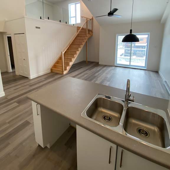 a kitchen with a double sink and a staircase in the background.