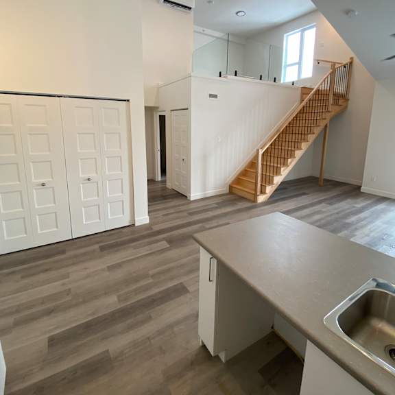 a kitchen with a sink and a staircase in the background.
