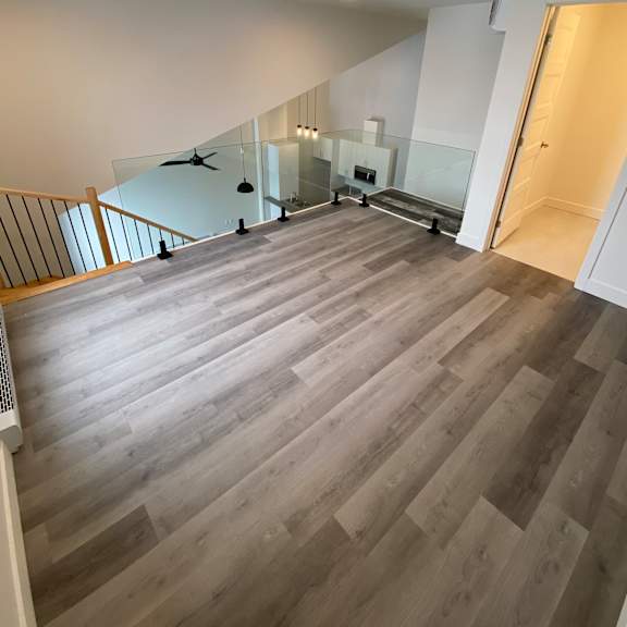 a spacious room with a staircase and a glass railing.