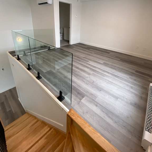 a room with a glass railing staircase.