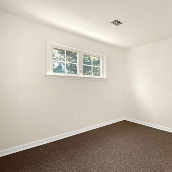 a room with a brown carpet and a window.